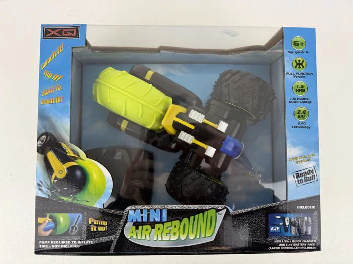En legetøjsbil i æske kaldet Mini Air Rebound med store hjul, hovedsageligt sort og gul, egnet til 6+ år og med fjernbetjening og luftdrevne hoppefunktioner.