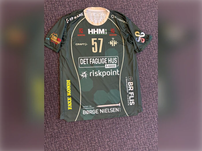 Grøn sportstrøje med nummer 57, flere sponsorlogoer og mønstre på et lilla mønstret tæppe. Trøjen har korte ærmer og tekst i gul, hvid og rød.