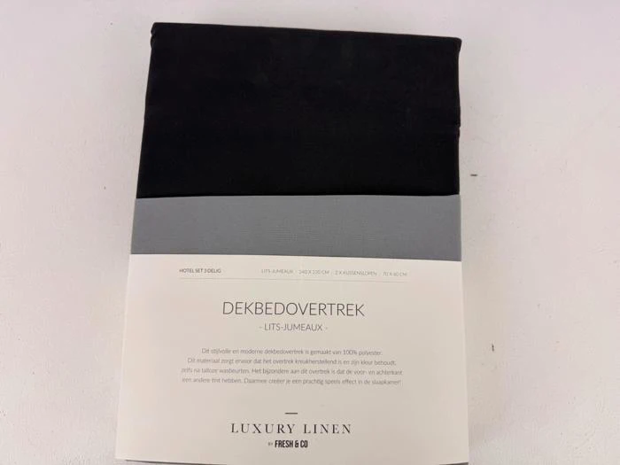 Et indpakket sort dynebetræk mærket DEKBEDOVERTREK med produktoplysninger på hollandsk og fransk, fra mærket Luxury Linen by Fresh & Co.