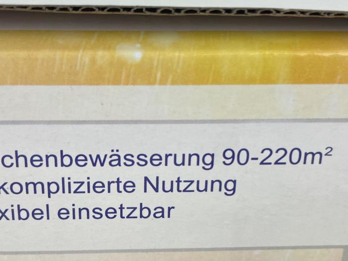 Den tyske tekst på emballagen lyder: "chenbewässerung 90-220m² komplizierte Nutzung xibel einsetzbar" på en gul og hvid baggrund.