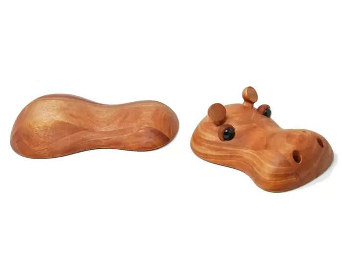 To træobjekter: Det ene er en abstrakt, buet form, og det andet ligner et flodhestehoved med runde ører, sorte øjne og næsebor.