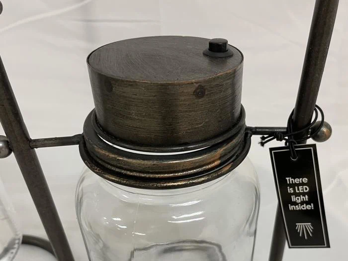 En glaskrukke med metallåg, der er fastgjort til et stativ, med et mærke, hvor der står: There is LED light inside!.