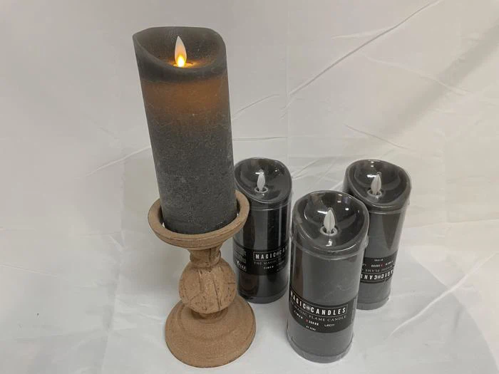Et sort flammeløst lys på en træholder er tændt og står ved siden af tre utændte sorte flammeløse lys på en hvid baggrund.