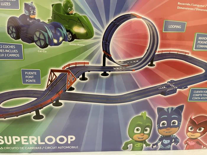 Legetøjsracerbane med sløjfe, bro og to biler. Nederst til højre ses figurer i grønne og blå kostumer med en farverig baggrund og mærkede funktioner.