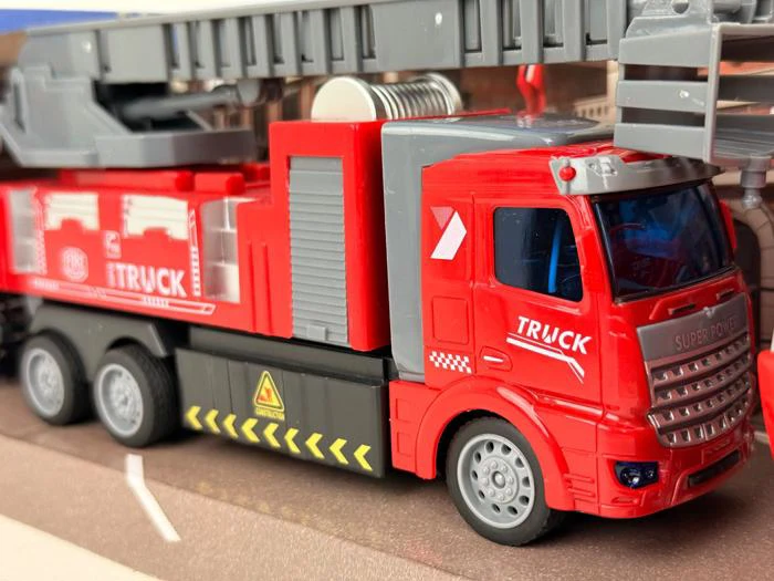 Nærbillede af en rød legetøjslastbil med TRUCK og SUPER POWER skrevet på siden, med flere hjul og detaljerede markeringer, placeret indendørs.
