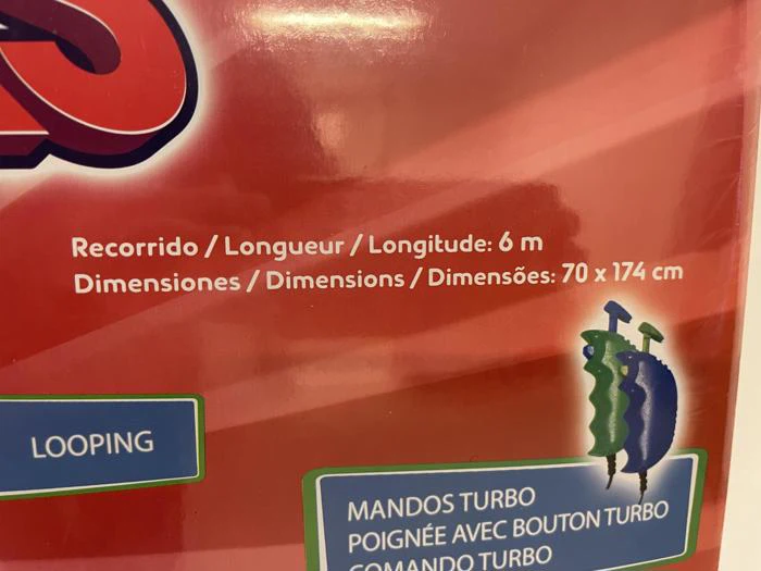 Nærbillede af produktemballage med tekst på flere sprog, der beskriver længde (6 meter) og dimensioner (70 x 174 cm), med farverig grafik på en rød baggrund.