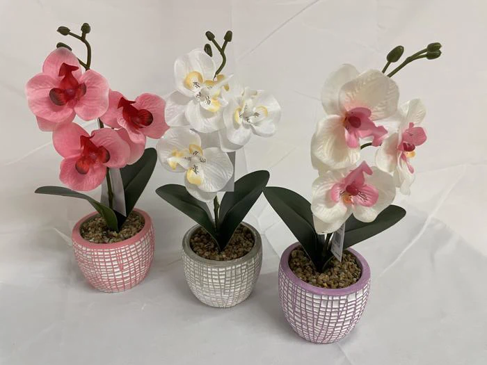Tre kunstige orkidéer i potter - pink, hvid og hvid med pink midte - er arrangeret i dekorative potter med et struktureret, gitterlignende design på en hvid baggrund.