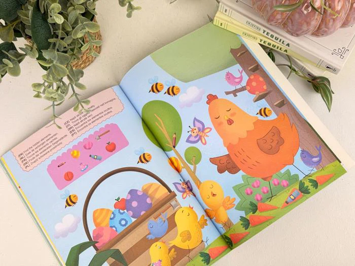 En åben børnebog viser farverige illustrationer af en høne, kyllinger, bier, blomster og æg med planter og bøger i baggrunden.