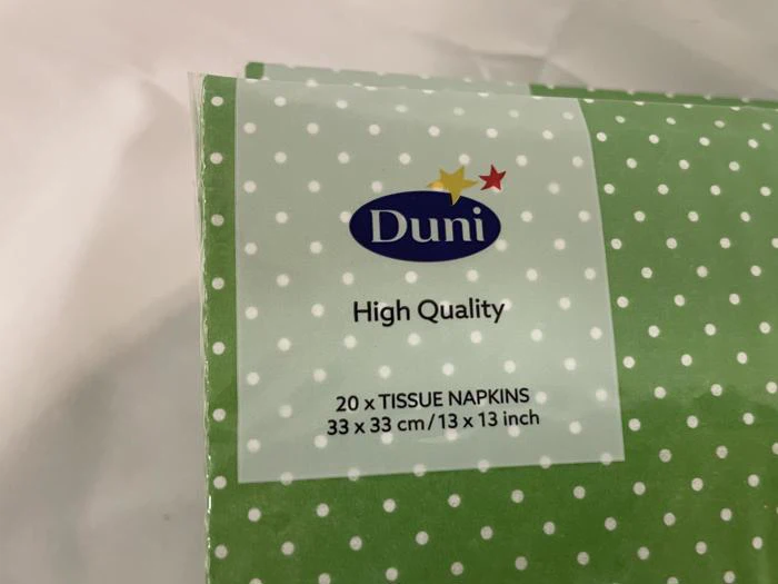 En grøn pakke Duni-servietter af høj kvalitet med hvide prikker; på etiketten står der 20 x TISSUE NAPKINS 33 x 33 cm / 13 x 13 inch.