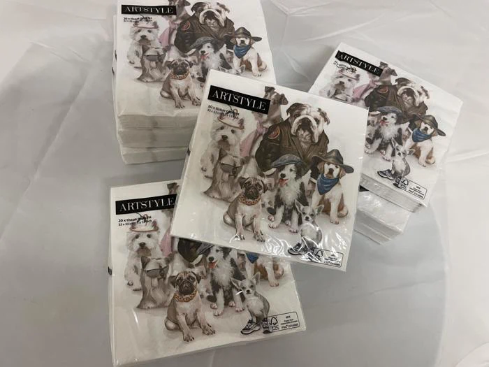 Flere pakker Artstyle-servietter med illustrationer af seks hunde i forskellige kostumer, arrangeret på en hvid overflade.