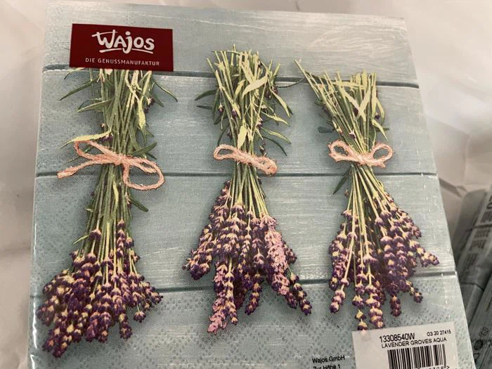 Tre bundter lavendel bundet med snor er arrangeret side om side på en lyseblå træoverflade. Wajos-logoet er i øverste venstre hjørne.