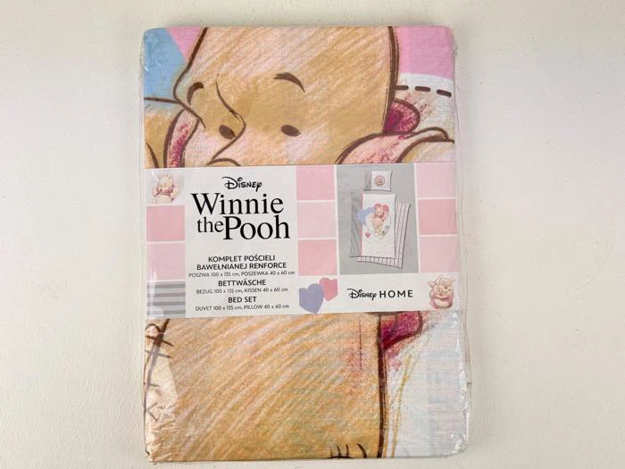 Et pakket Disney Winnie the Pooh-sengesæt med en stor illustration af Plys, der holder Grisling. Emballagen viser sættets detaljer og et lille billede af sengesættets design.