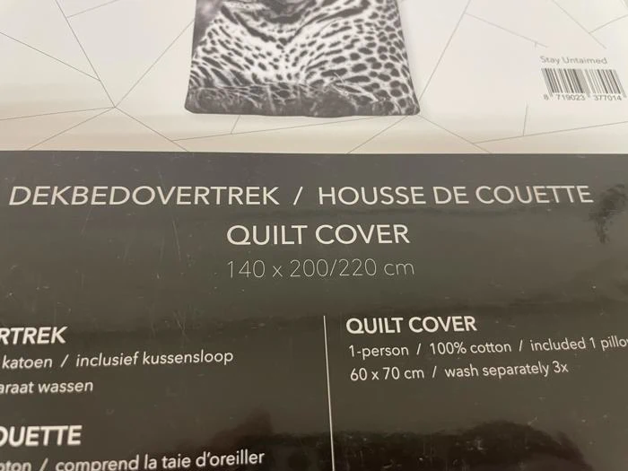 Nærbillede af emballagen til dynebetræk med tekst på hollandsk, fransk og engelsk. Angivne mål: 140 x 200/220 cm. Sort og hvidt design med et leopardbillede på toppen.