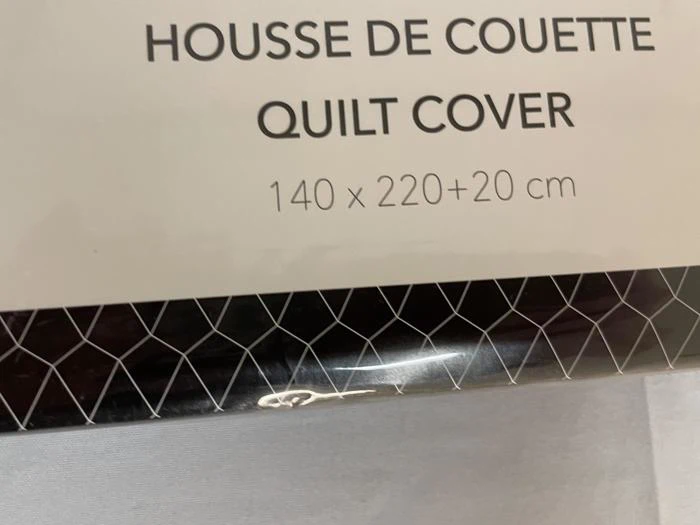 En pakke mærket Housse de Couette Quilt Cover 140 x 220+20 cm med et geometrisk mønster i bunden.
