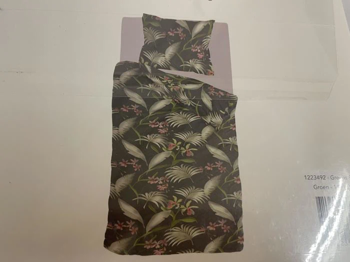 Et sengesæt med grønt bladmønster og rosa blomster, inklusive dynebetræk og matchende pudebetræk, vist på en lys baggrund.