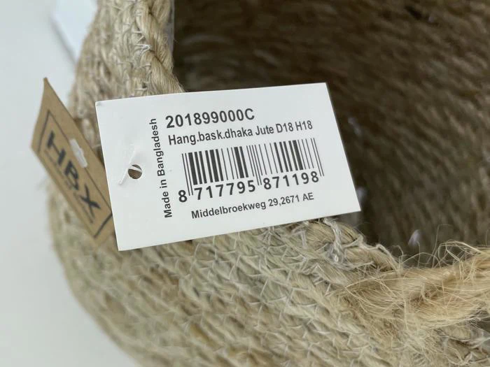 Nærbillede af en vævet jutekurv med et produktmærke, der viser en stregkode, produktoplysninger og teksten Made in Bangladesh.