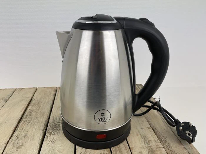 En elkedel i rustfrit stål med et sort håndtag og en netledning, placeret på en træoverflade. Kedlen har et YKU-logo på forsiden.