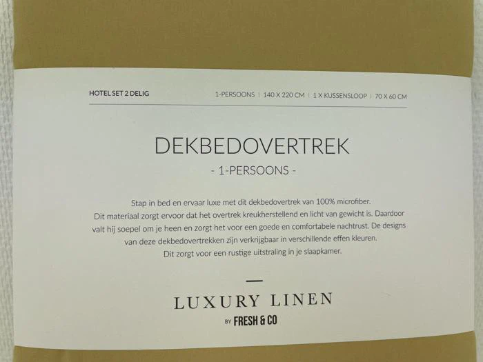 En etiket til et luksusdynebetræk i hør til én person på hollandsk med oplysninger om størrelse, materiale og funktioner, og mærket Fresh & Co står nederst.