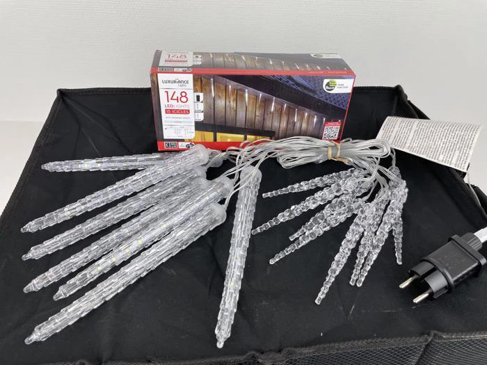 Et sæt istappeformede LED-lyskæder med et tostrenget stik vises frem foran emballagen med 148 LED-lys til udendørs brug.
