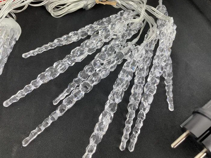 Ispindeformet lyskæde i klar plast med stik, lagt ud på en sort flade.