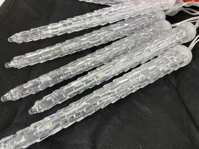 Nærbillede af flere istappeformede LED-lys i klar plast, der ligger på en sort stofoverflade.