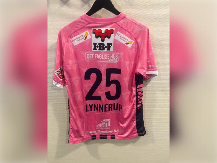 Bagside af en lyserød fodboldtrøje med nummeret 25 og navnet LYNNERUP trykt på ryggen samt forskellige sponsorlogoer.