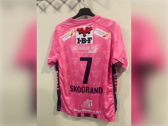 Lyserød fodboldtrøje med nummer 7 og navnet SKOGRAND på ryggen samt forskellige sponsorlogoer.