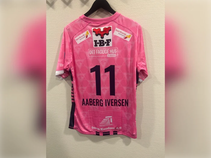 Lyserød og sort sportstrøje med nummeret 11, navnet AABERG IVERSEN og forskellige sponsorlogoer trykt på ryggen.