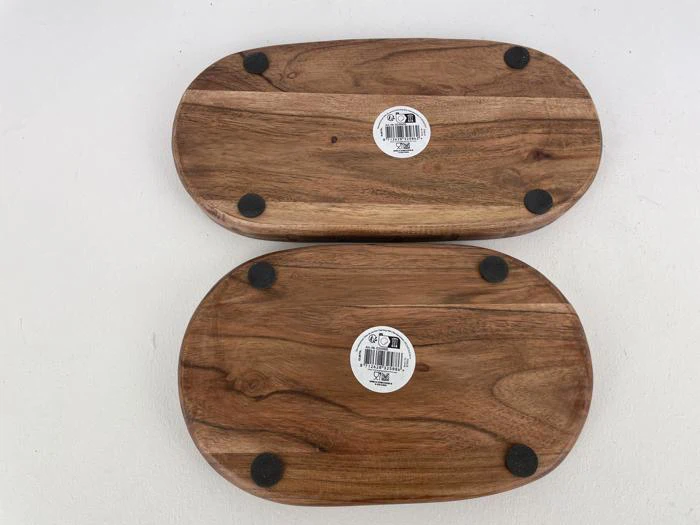 To skærebrætter af træ med runde sorte puder og klistermærker på bunden, placeret side om side på en hvid overflade.