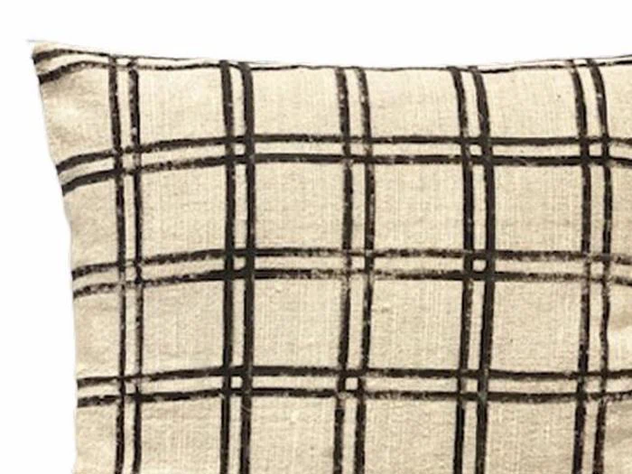 En beige pude med et sort, håndtegnet ternet mønster af krydsende vandrette og lodrette linjer.