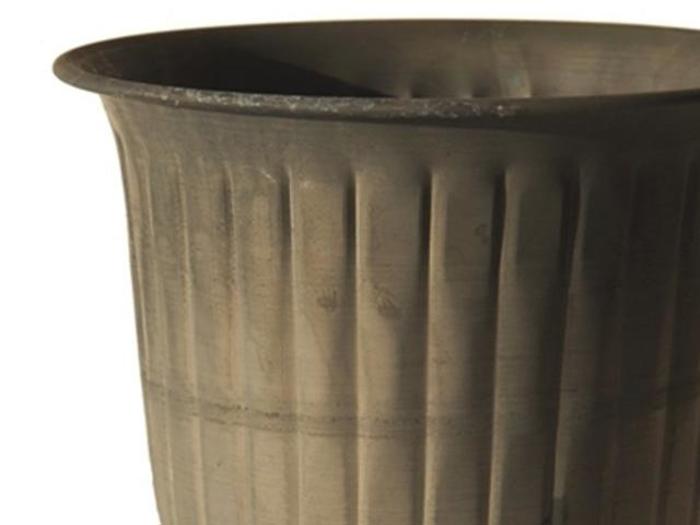 Et nærbillede af den øverste halvdel af en ribbet, cylindrisk, mørkfarvet potte eller beholder mod en almindelig baggrund.