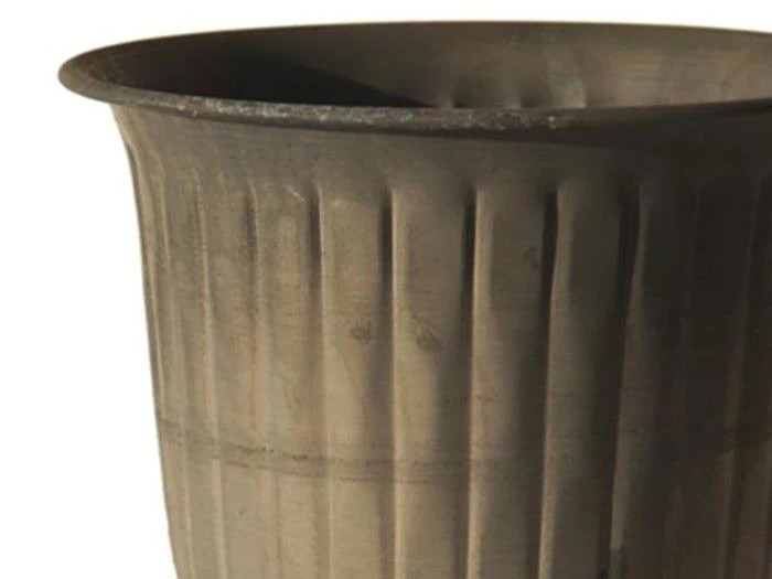 Et nærbillede af den øverste halvdel af en ribbet, cylindrisk, mørkfarvet potte eller beholder mod en almindelig baggrund.