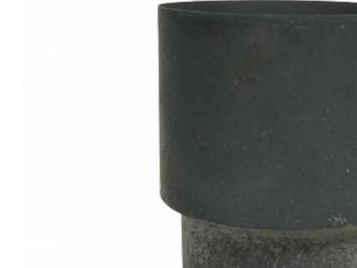 Et nærbillede af et sort cylindrisk objekt med en glat overflade på en almindelig hvid baggrund.