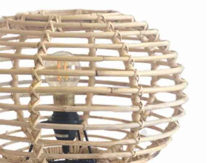 Nærbillede af en rund, flettet lampeskærm i rattan med en synlig pære indeni mod en hvid baggrund.