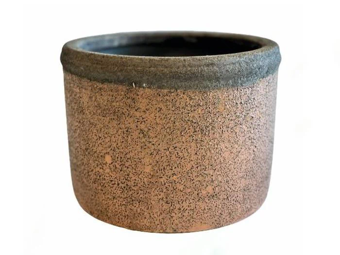 En rund, bred, rustik lerkrukke med en struktureret, spættet overflade og en mørk kant på en almindelig hvid baggrund.