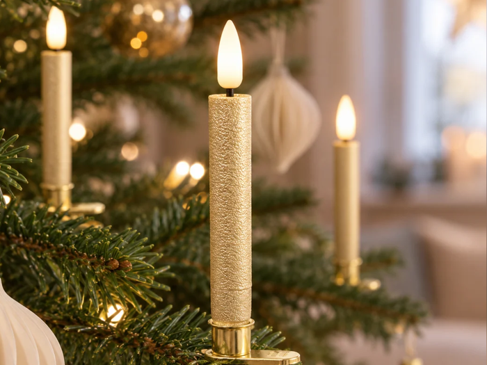 Tre elektriske, tilspidsede stearinlys, der lyser på et juletræ.