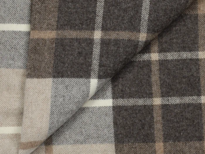 Nærbillede af to overlappende stykker uldstof med brune, beige og cremefarvede ternede mønstre. Det ene stof er lagt diagonalt over det andet.