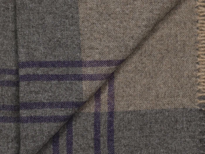 Nærbillede af et uldstof med ternet mønster i grå og beige, med krydsende mørklilla linjer og blød tekstur.