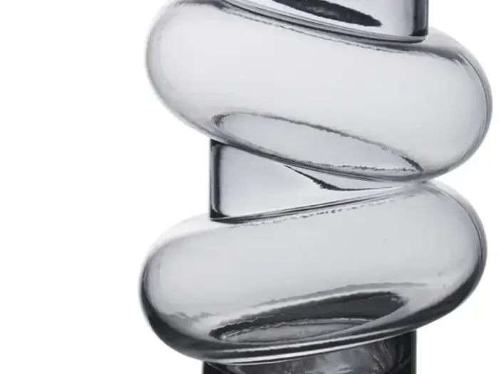 Et nærbillede af en klar glasgenstand med et spiralformet twist-design på en hvid baggrund.