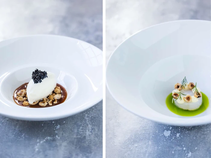 To hvide skåle: den ene med en skefuld cremet dessert toppet med sort kaviar på nødder og sauce; den anden med en lille bunke i grøn olie, pyntet med krydderurter og hasselnødder.