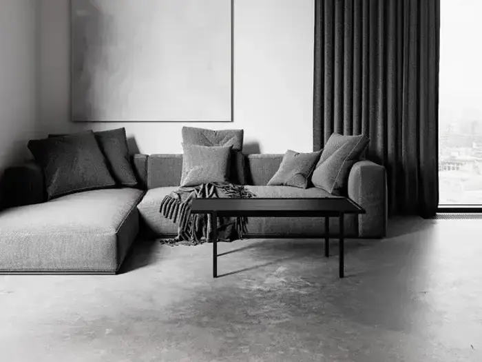 En moderne stue med en grå sektionssofa, flere puder, et tæppe, et sort sofabord, mørke gardiner og et stort abstrakt maleri på væggen.