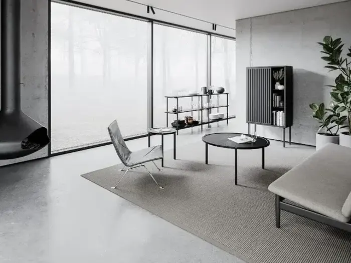 Minimalistisk stue med store vinduer, moderne møbler, et gråt tæppe, et sort rundt sofabord, planter og en ophængt sort pejs.