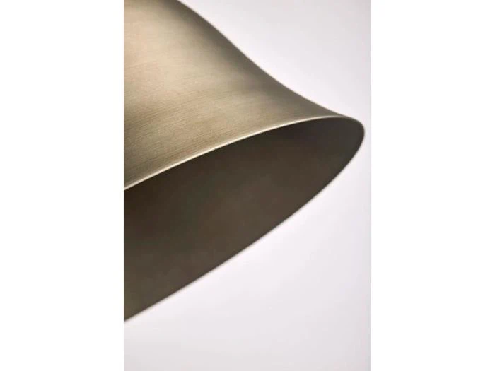 Nærbillede af en metallisk, klokkeformet lampeskærm mod en almindelig hvid baggrund, fotograferet fra en sidevinkel.