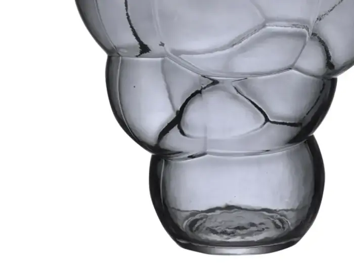 Nærbillede af en gennemsigtig, struktureret glasvase med afrundede, boblelignende former på en hvid baggrund.