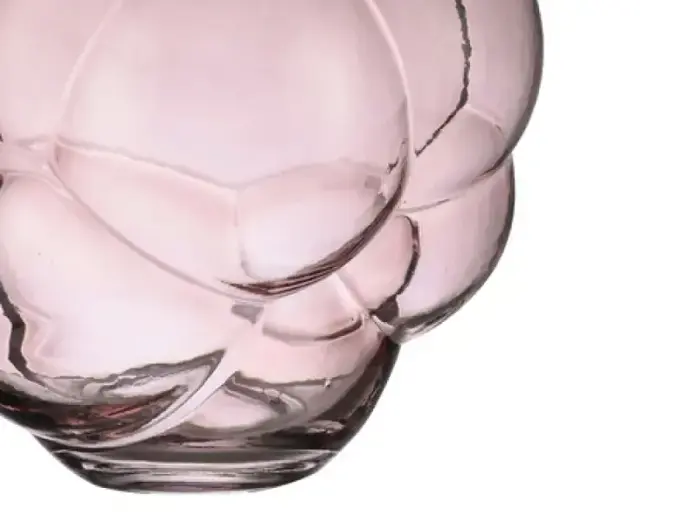 Nærbillede af en lyserød, gennemskinnelig glasvase med et boblelignende, afrundet mønster på en hvid baggrund.