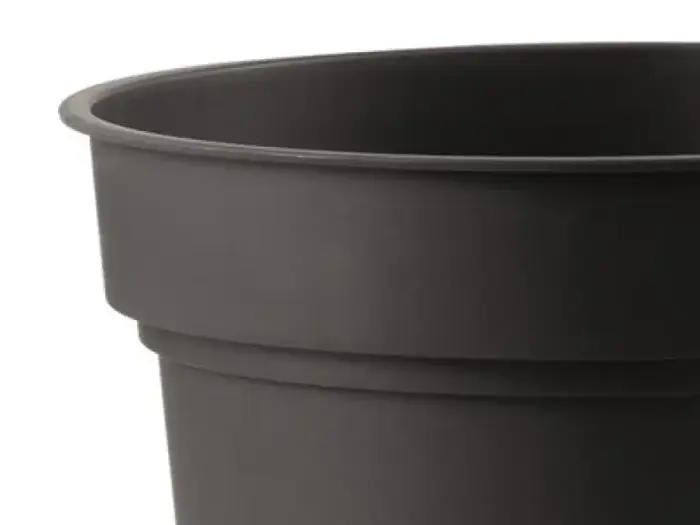 Et nærbillede af en almindelig, tom sort plastikpotte mod en hvid baggrund.