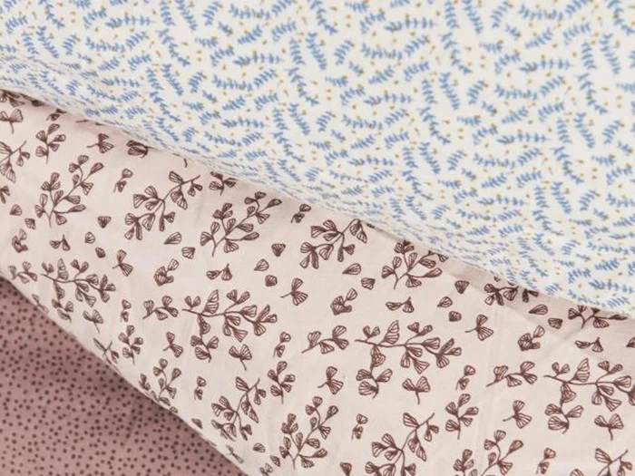 Tre ruller stof med forskellige små blomster- og bladmønstre i blå, brune og rosa nuancer.