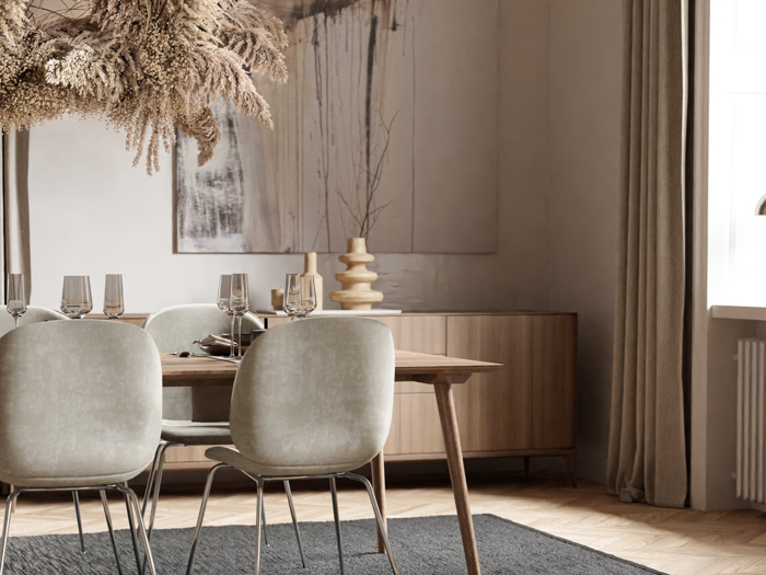 En moderne spisestue med lysegrå stole, et træbord med glas, tørrede blomster over, neutrale kunstværker og blødt naturligt lys fra et nærliggende vindue.