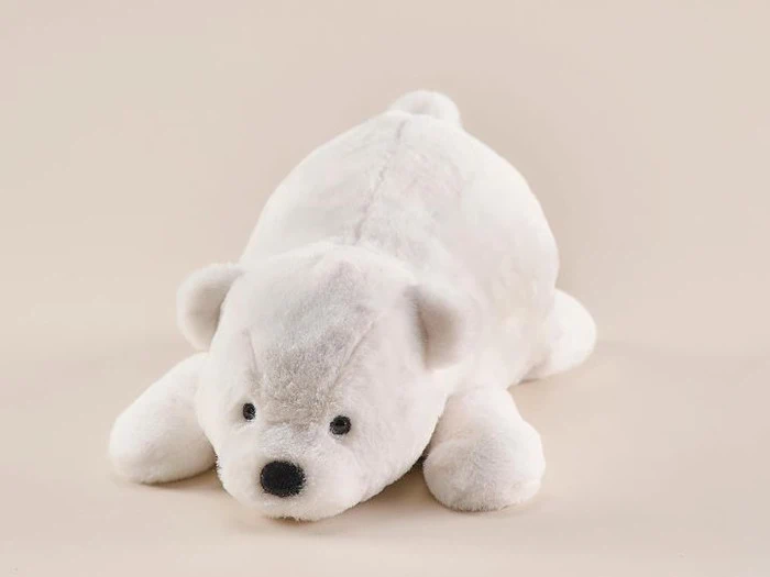 En hvid isbjørn i plys ligger på en lys beige overflade, vender fremad med spredte ben og en sort næse og øjne.