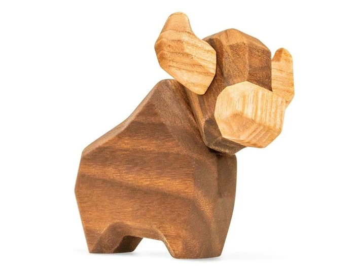 En lille, stiliseret træfigur af en bison med kantede træk og lysere horn, der står på en hvid baggrund.